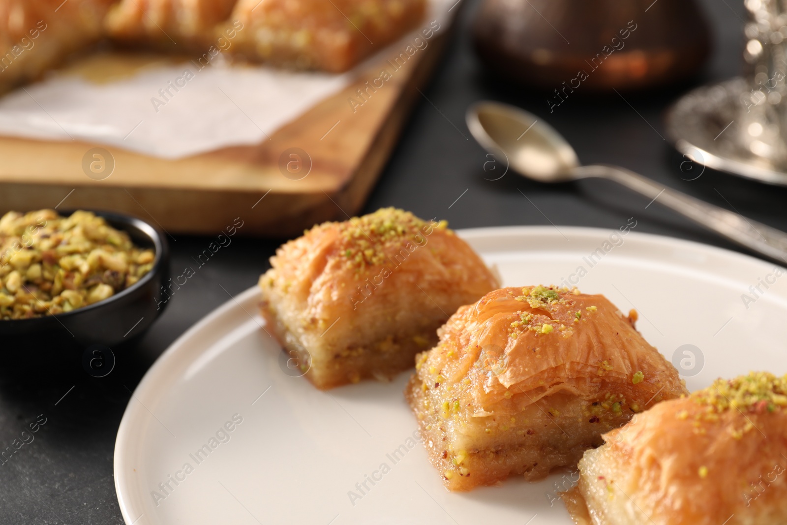 Photo of Delicious sweet baklava with pistachios on black table, closeup