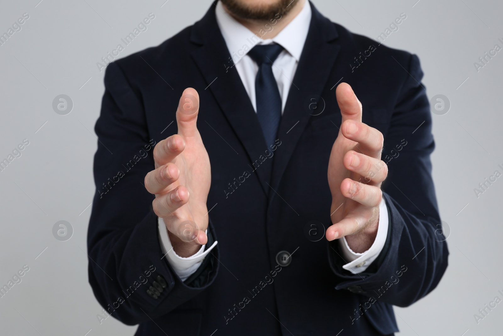 Photo of Businessman holding something against grey background, focus on hands