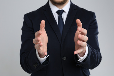 Photo of Businessman holding something against grey background, focus on hands