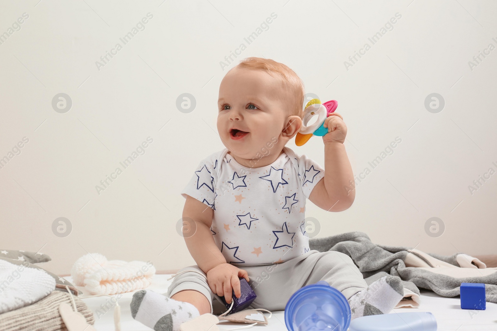 Photo of Little boy in cute clothes sitting on floor against light background. Baby accessories