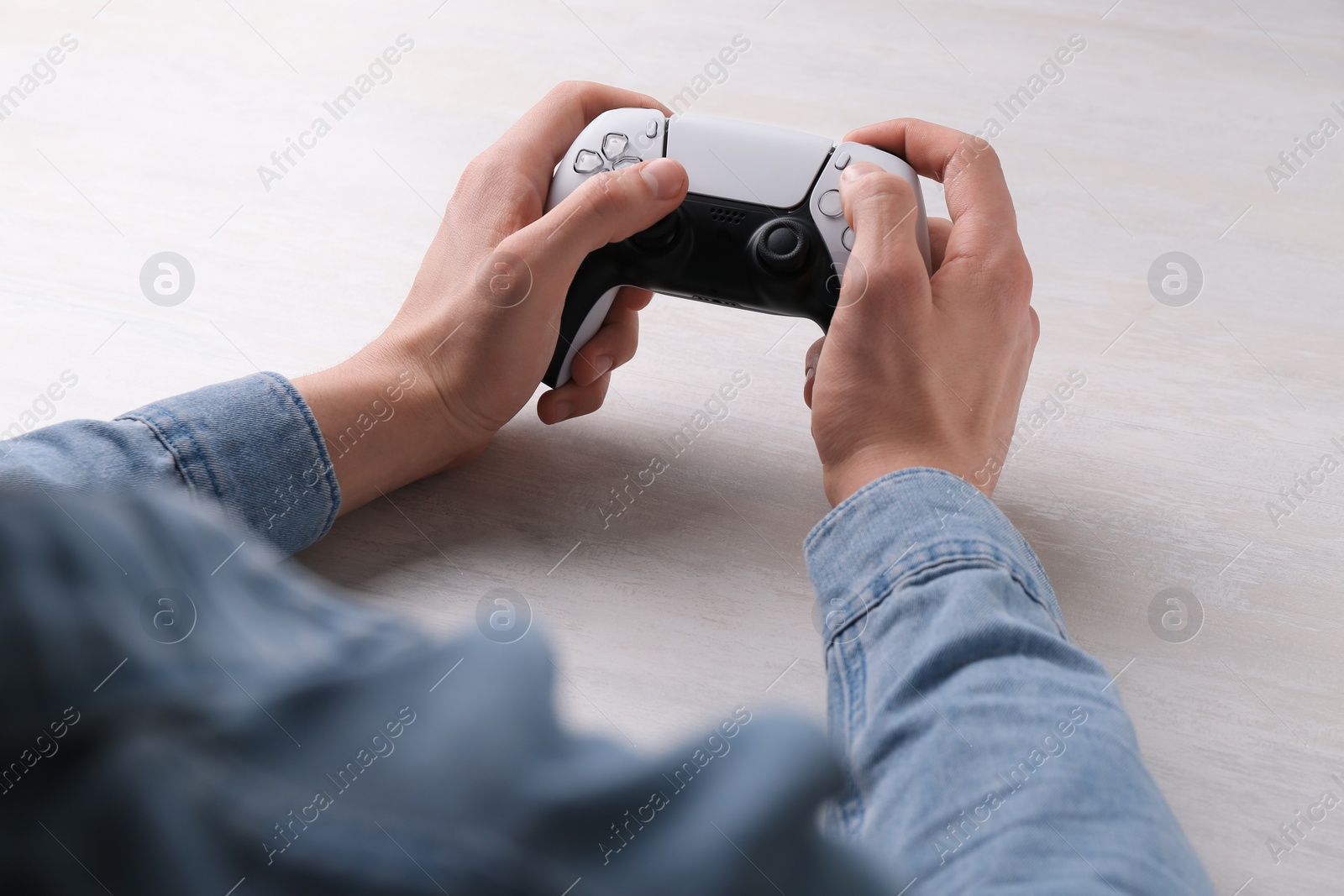 Photo of Man using wireless game controller at white table, closeup