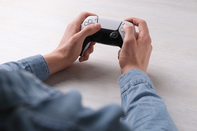 Man using wireless game controller at white table, closeup