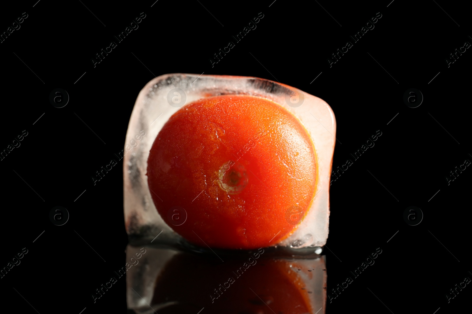 Photo of Ripe frozen tomato on dark table. Keeping vegetables fresh