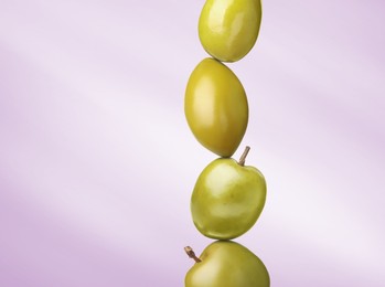 Image of Stack of whole green olives on violet gradient background
