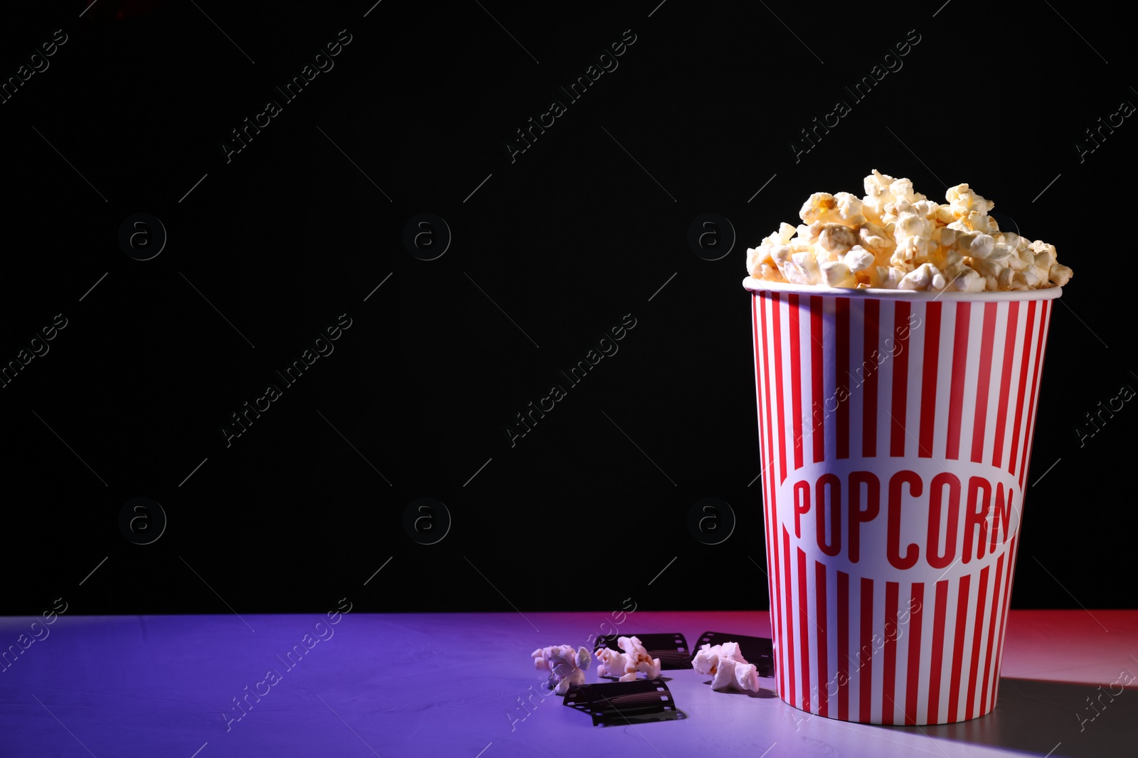 Photo of Delicious popcorn and tape on table. Space for text