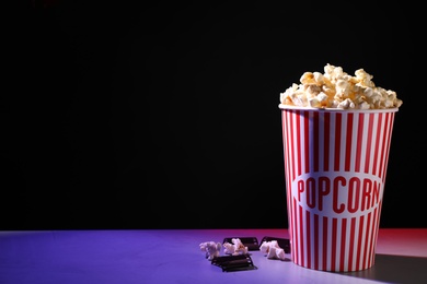 Photo of Delicious popcorn and tape on table. Space for text