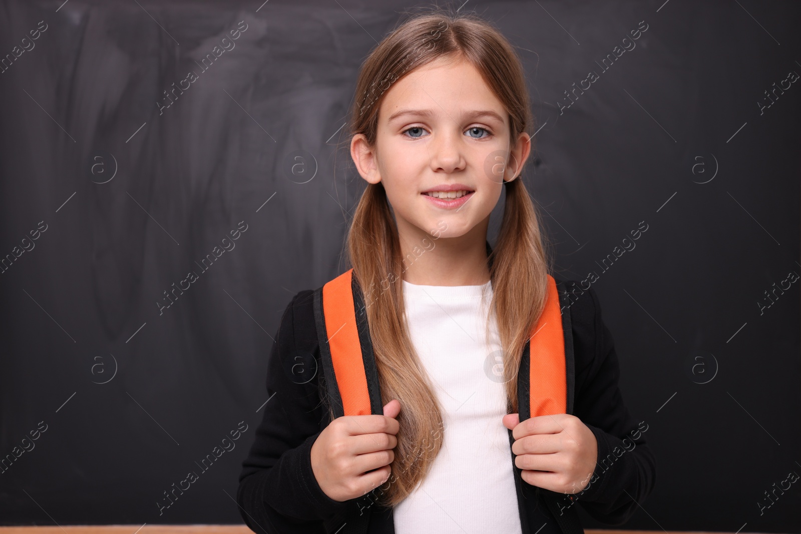 Photo of Back to school. Smiling girl near blackboard