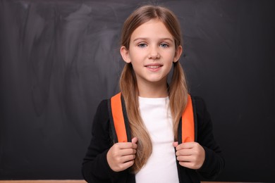 Photo of Back to school. Smiling girl near blackboard