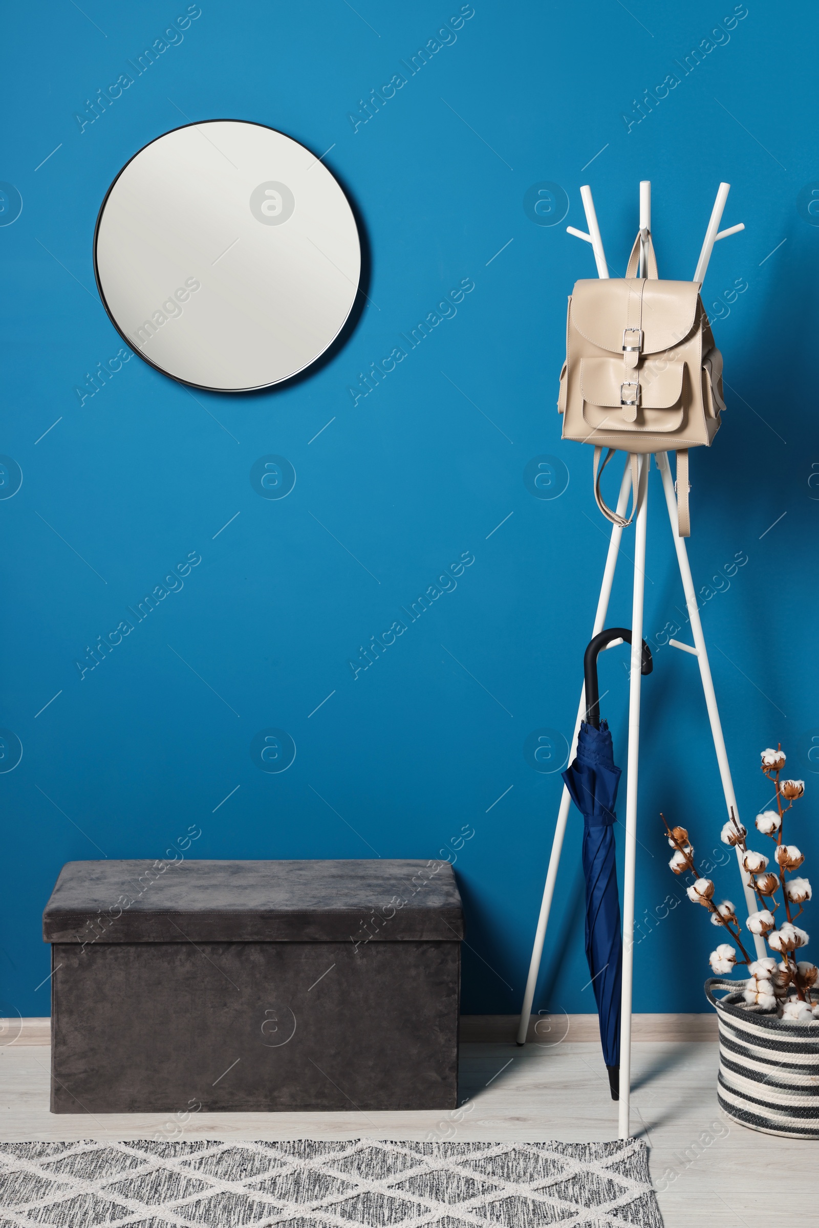 Photo of Stylish hallway with blue wall, mirror and clothing rack. Interior design