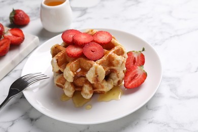 Photo of Delicious Belgian waffles with strawberries and honey on white marble table, closeup