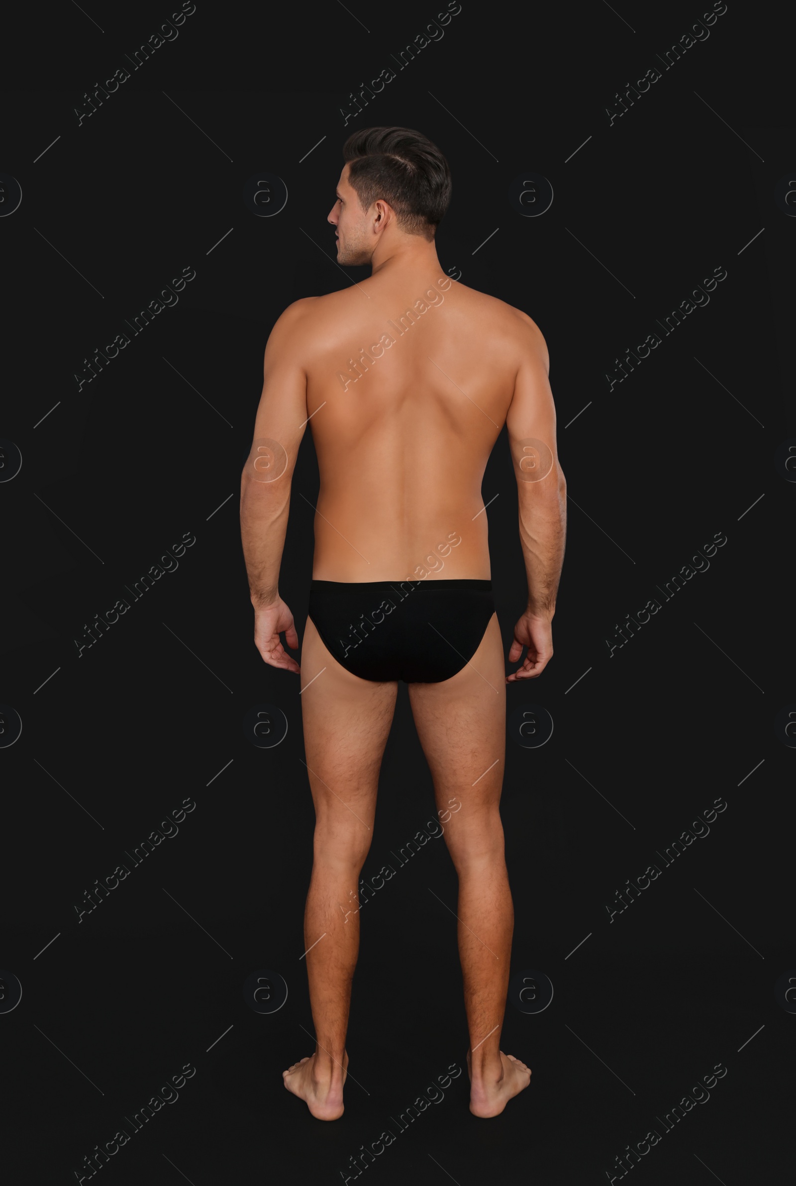 Photo of Man in underwear on black background, back view