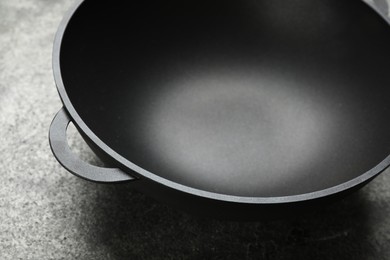 Empty iron wok on grey table, closeup. Chinese cookware