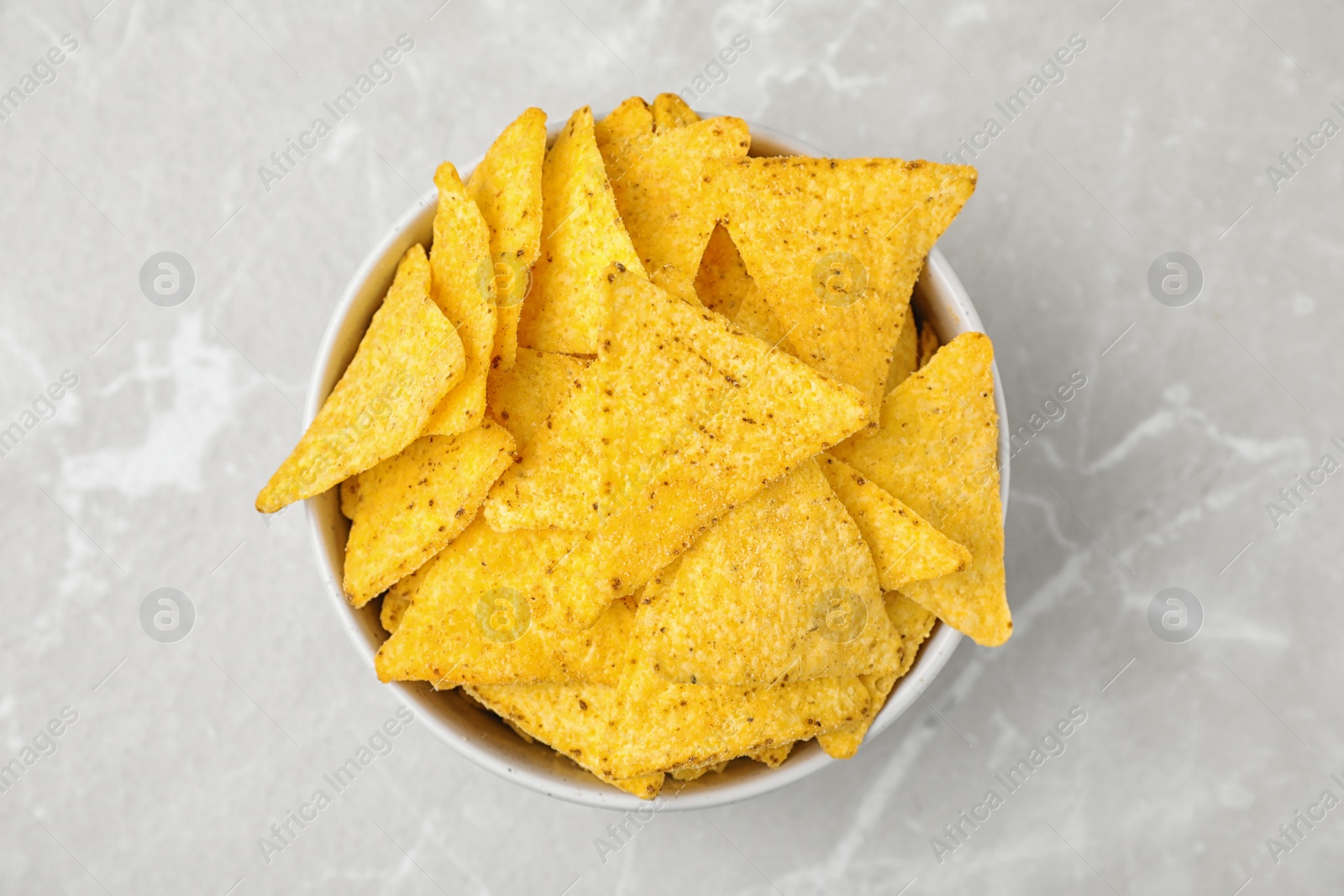 Photo of Bowl with tasty Mexican nachos chips on grey table, top view