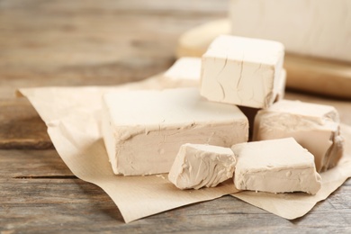 Photo of Pieces of compressed yeast on wooden table, closeup