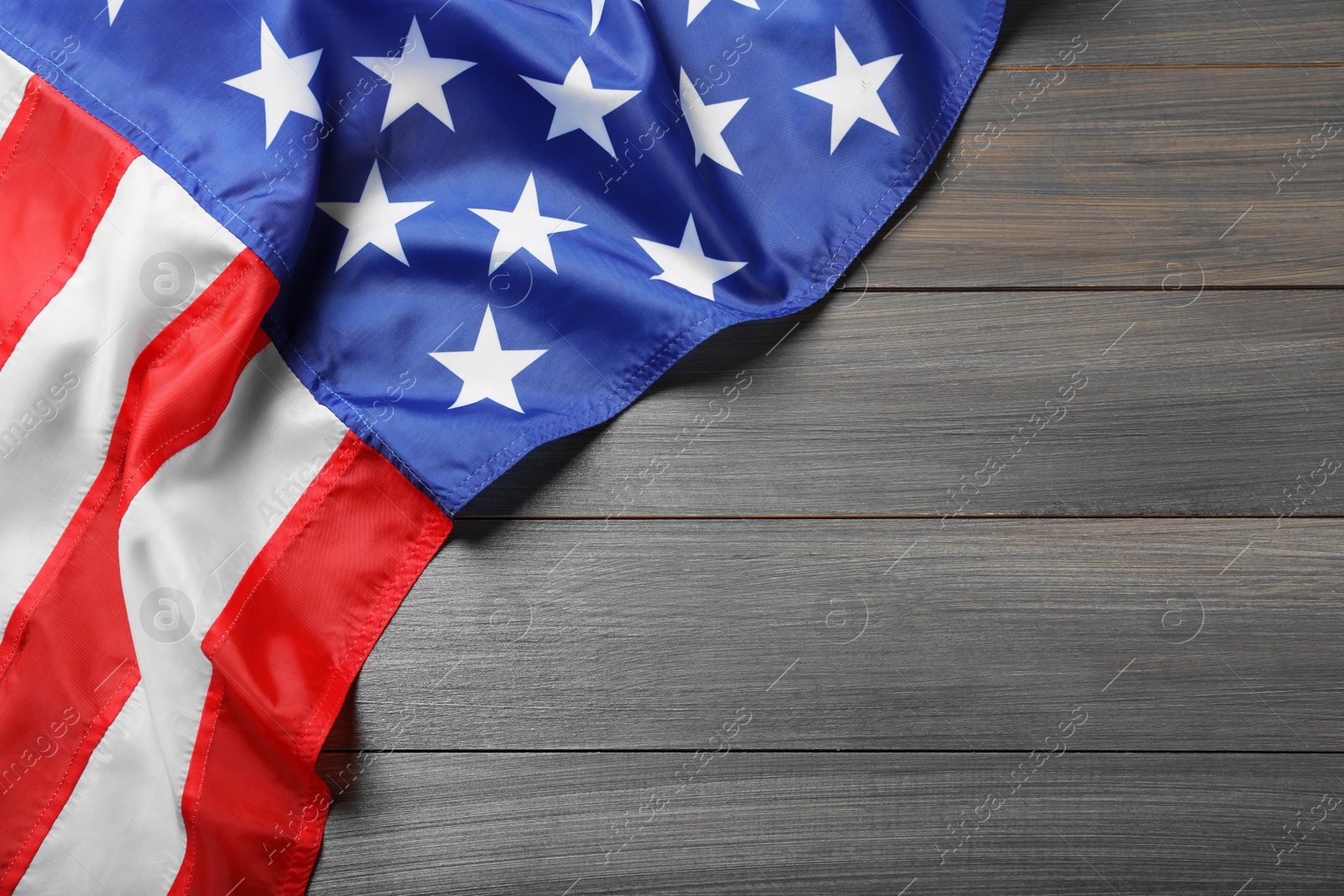 Photo of American flag on wooden table, top view. Space for text