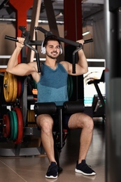 Young man with headphones listening to music and working out at gym