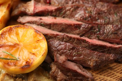 Photo of Delicious grilled beef with lemon on table, closeup