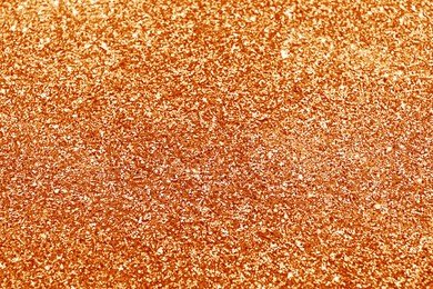 Image of Beautiful shiny orange glitter as background, closeup