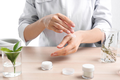 Photo of Woman applying natural cream onto hand in cosmetic laboratory, closeup