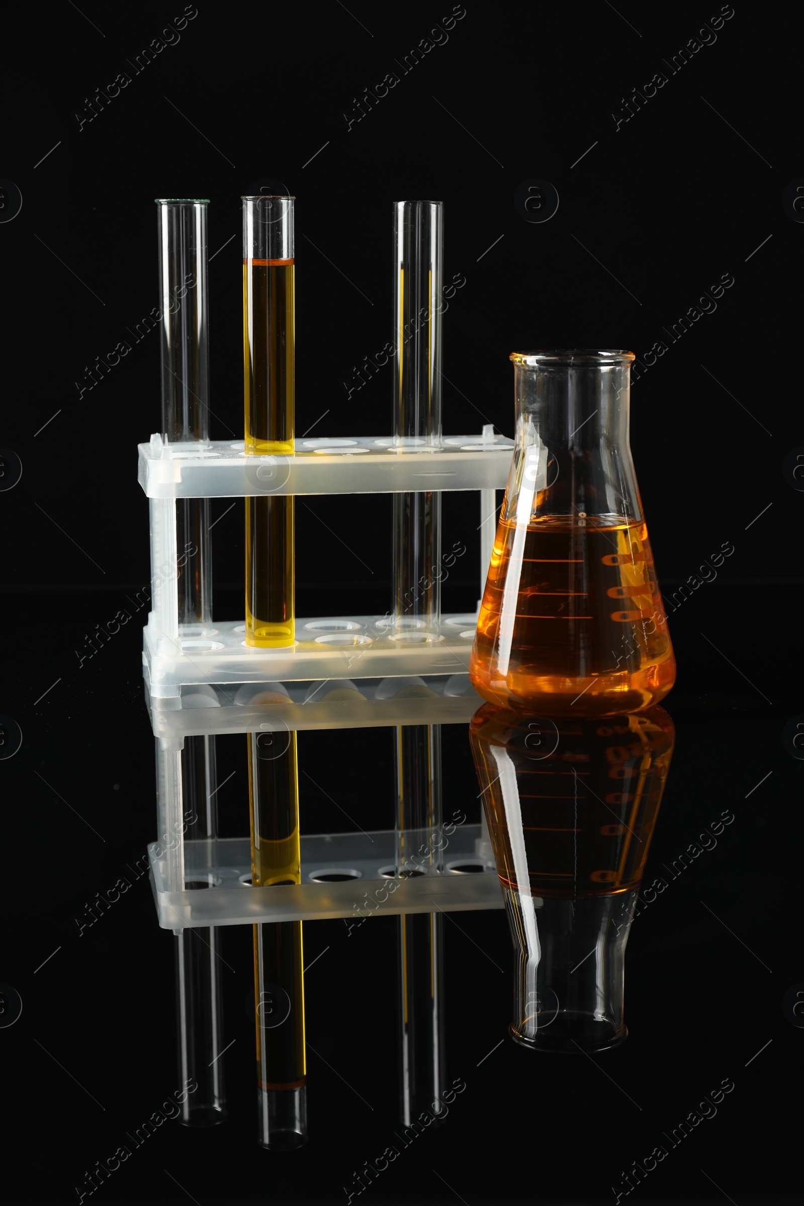 Photo of Laboratory glassware with different types of oil on black background