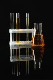 Laboratory glassware with different types of oil on black background