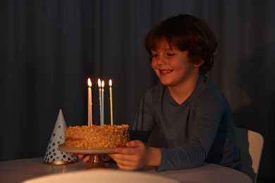 Photo of Cute boy with birthday cake at table indoors