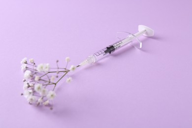 Cosmetology. Medical syringe and gypsophila on violet background