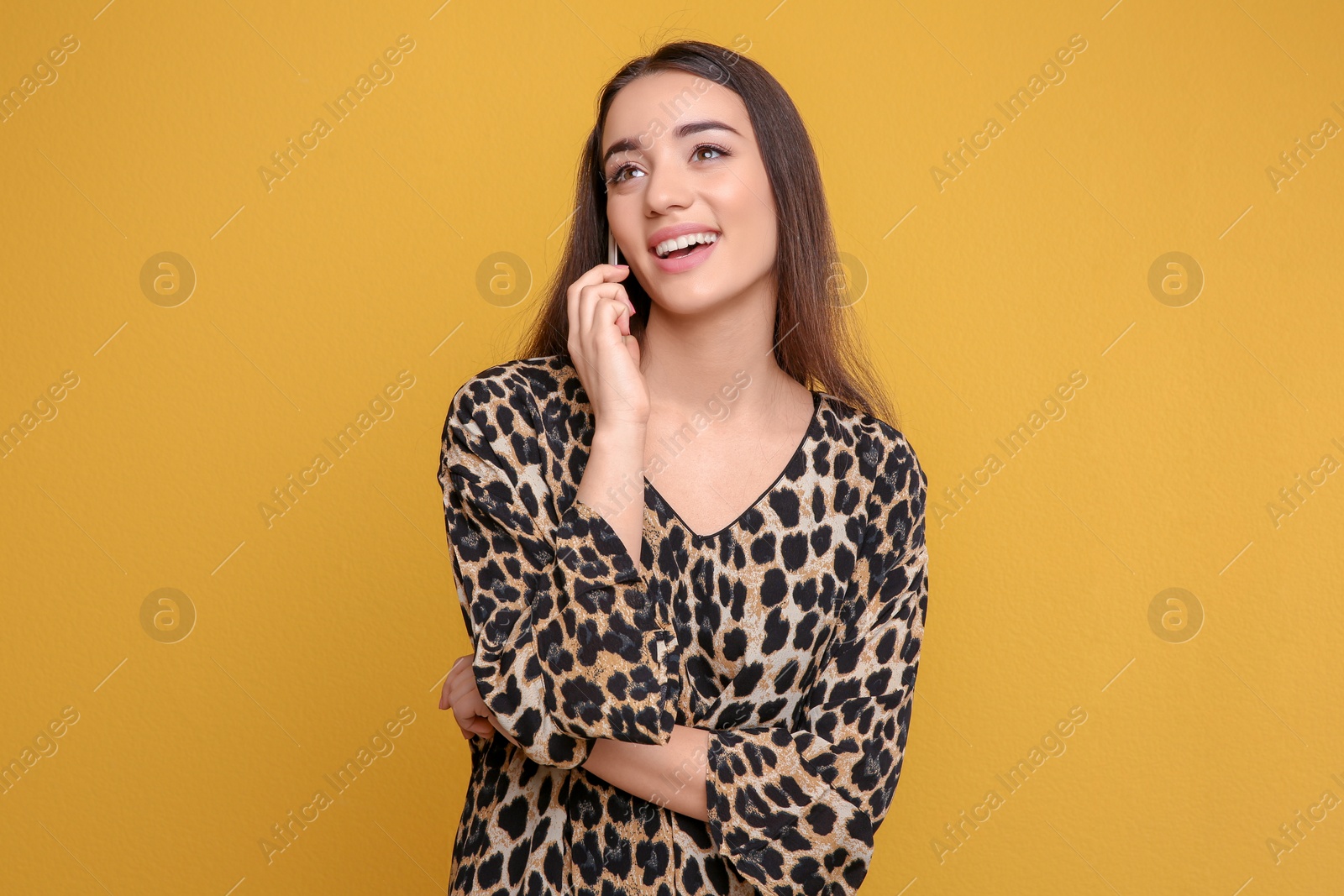 Photo of Attractive young woman talking on mobile phone against color background