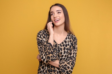 Photo of Attractive young woman talking on mobile phone against color background