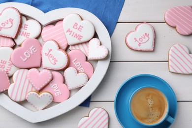 Photo of Delicious heart shaped cookies and cup of coffee on white wooden table, flat lay