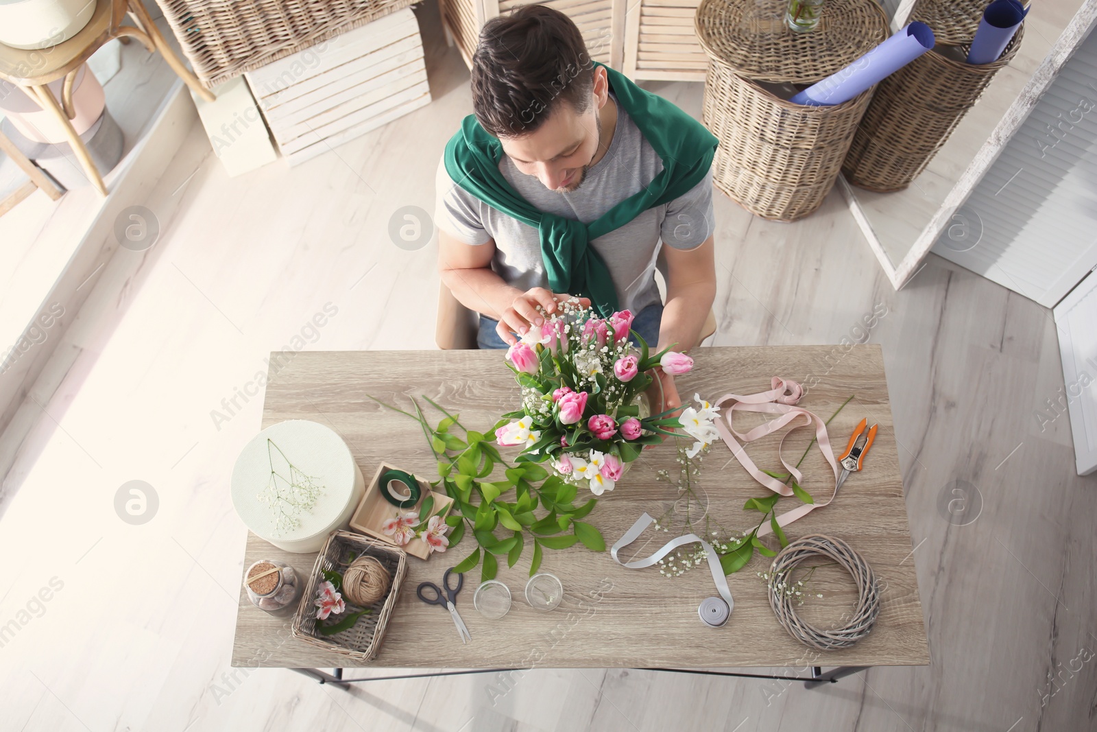 Photo of Male decorator creating beautiful bouquet at table, top view