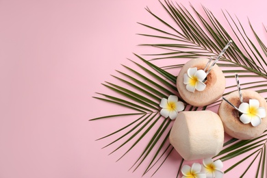 Photo of Fresh coconuts with drinking straws and flowers on pink background, flat lay. Space for text