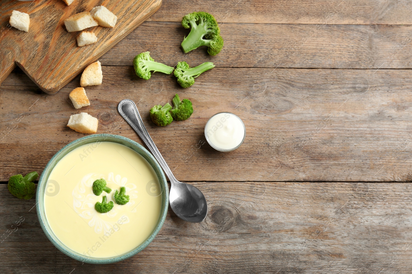 Photo of Flat lay composition with bowl of cheese cream soup and broccoli on wooden table, space for text