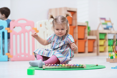Cute little child playing with xylophone on floor