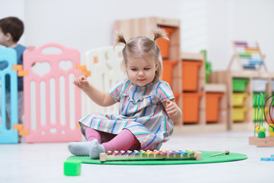 Photo of Cute little child playing with xylophone on floor