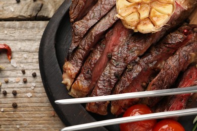 Delicious grilled beef with tomatoes and spices on wooden table, top view