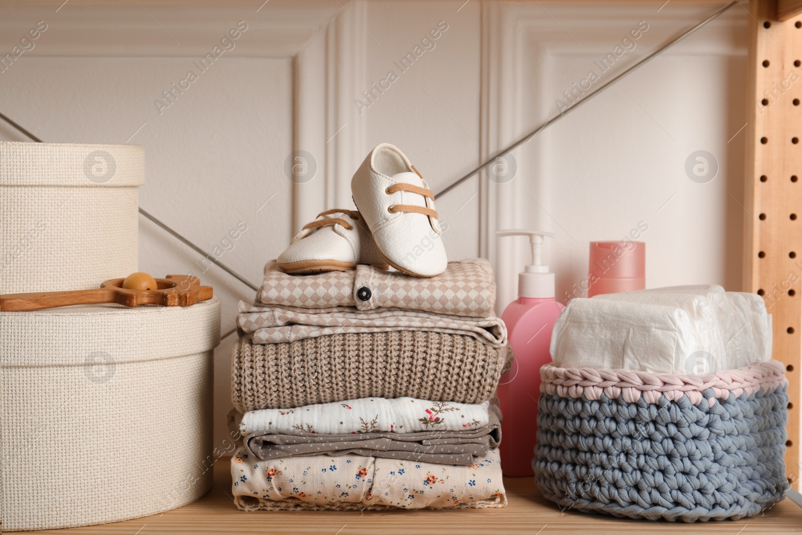 Photo of Baby clothes, shoes and accessories on wooden rack