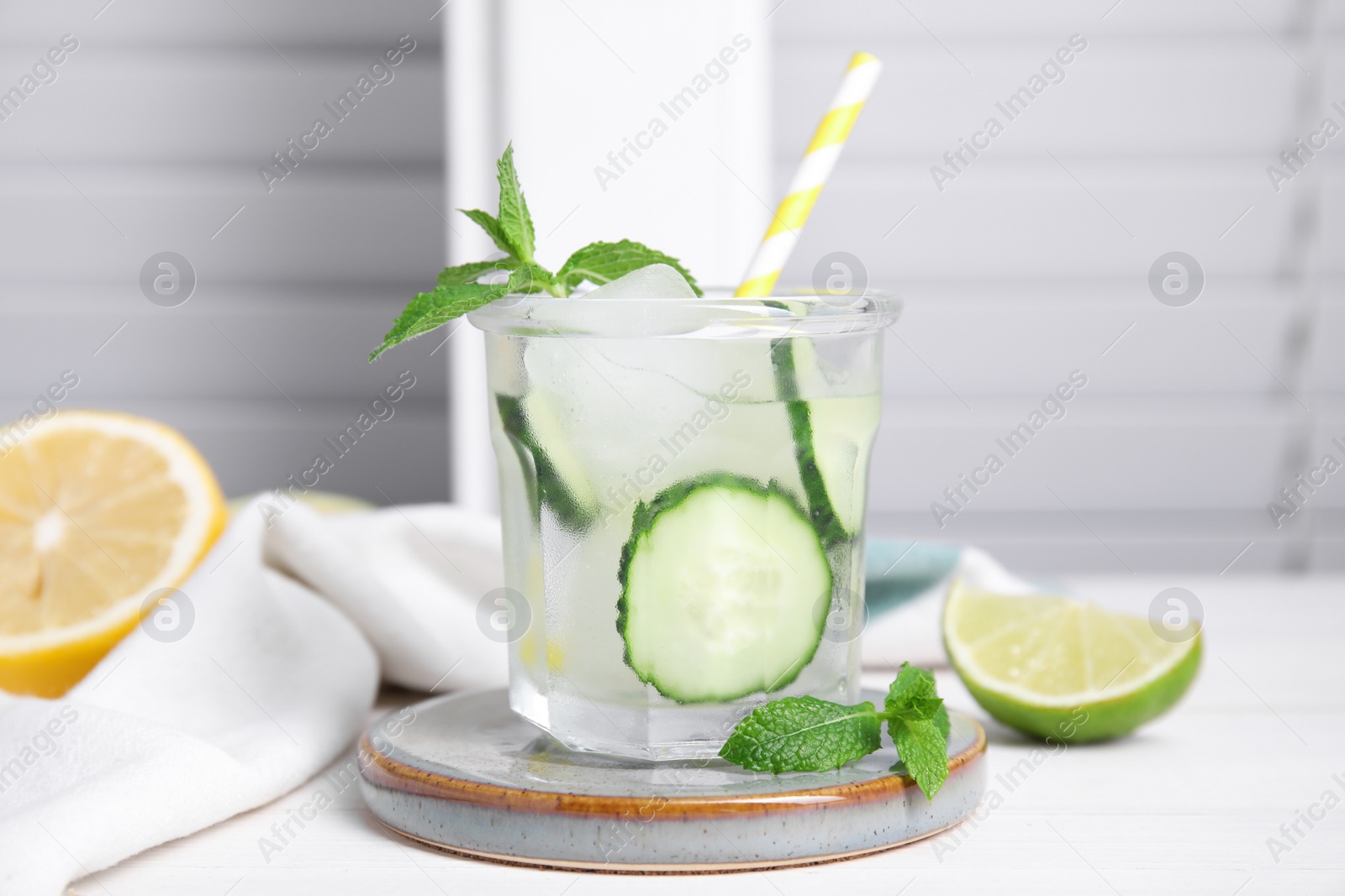 Photo of Glass of refreshing cucumber water with mint on white wooden table