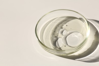 Photo of Petri dish with liquid sample on light background, closeup. Space for text