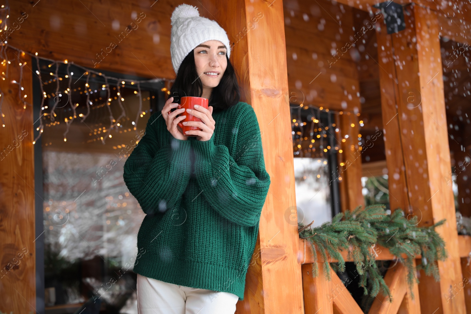 Photo of Pretty woman wearing sweater with cup near wooden terrace in winter