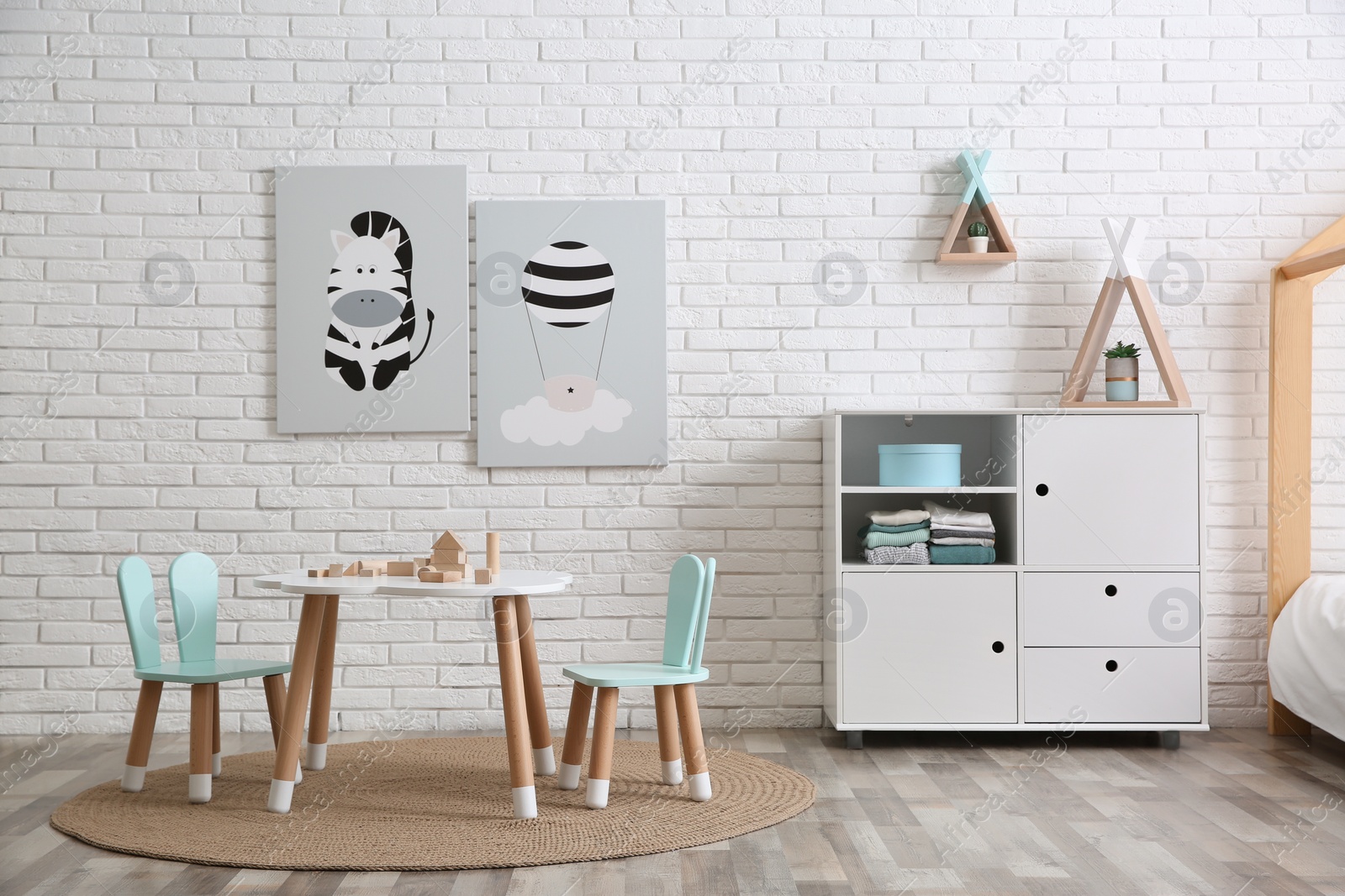 Photo of Cute children's room interior with little table near white brick wall