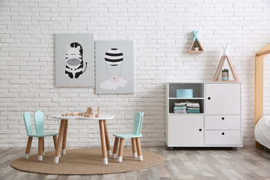 Cute children's room interior with little table near white brick wall