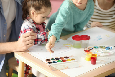 Photo of Lovely family painting at table indoors. Playing with children