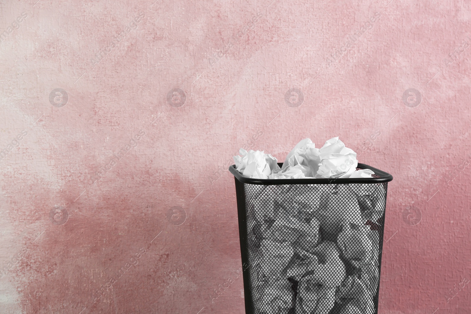 Photo of Basket with crumpled paper on pink background. Space for text