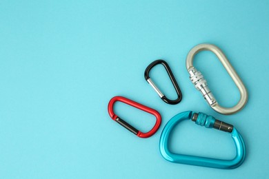 Photo of Metal carabiners on light blue background, flat lay. Space for text