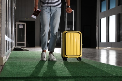 Photo of Man with yellow travel suitcase in airport
