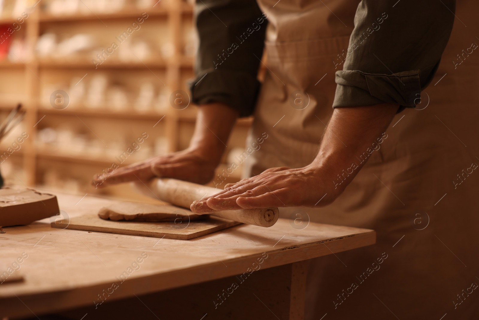 Photo of Man crafting with clay at table indoors, closeup