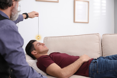 Photo of Psychotherapist using pendulum during hypnotherapy   session in office