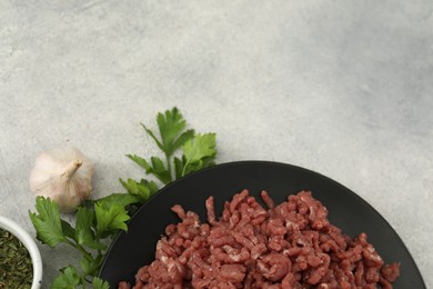 Photo of Minced meat, parsley, garlic and spices on grey table, flat lay. Space for text