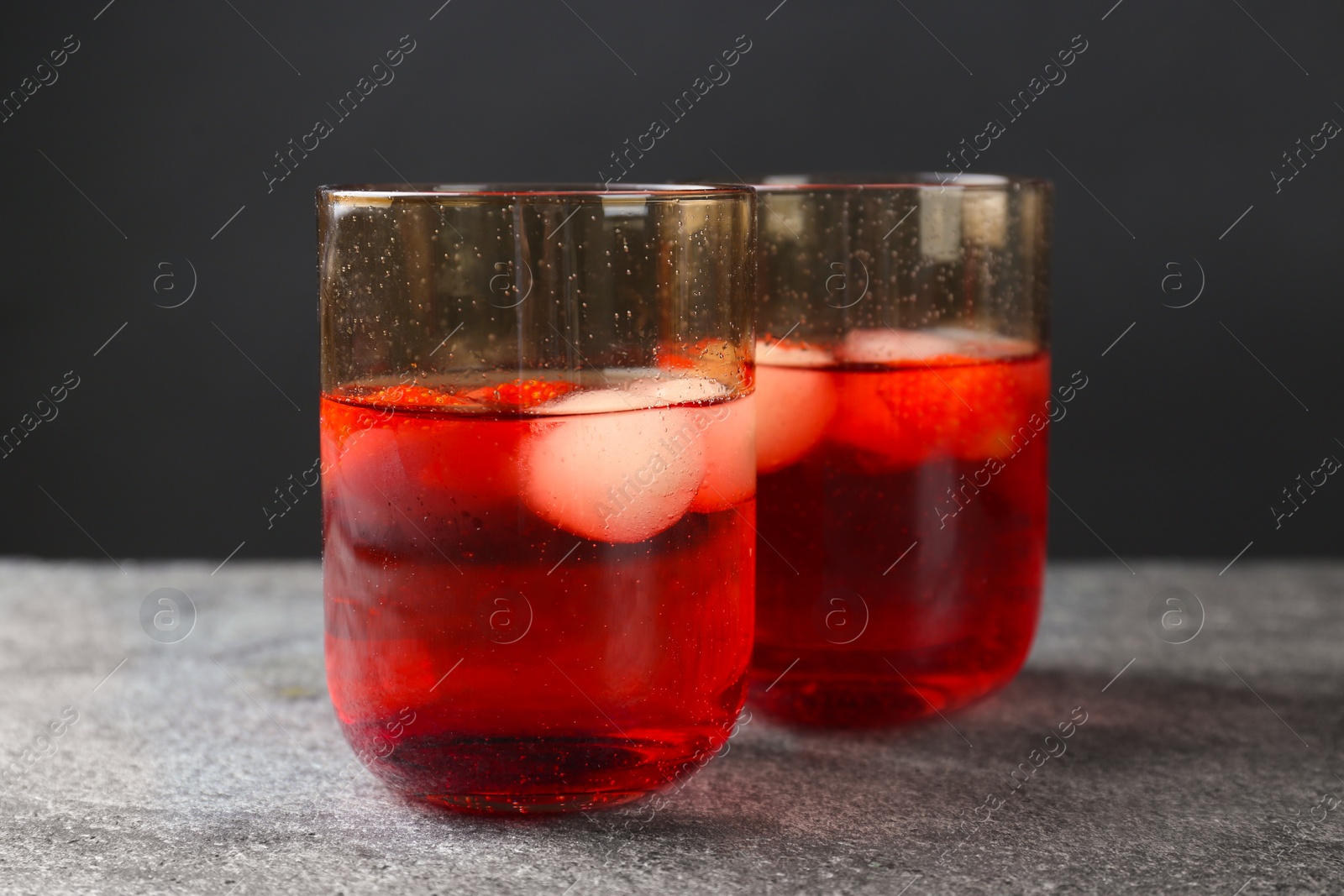 Photo of Delicious cocktails with strawberries and ice balls on grey table